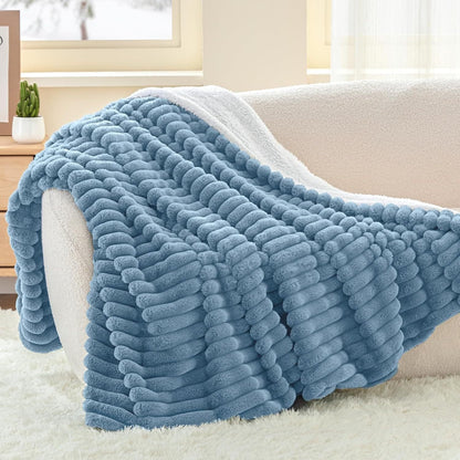 Couverture douce Homyset coloris Bleu, pliée sur un canapé